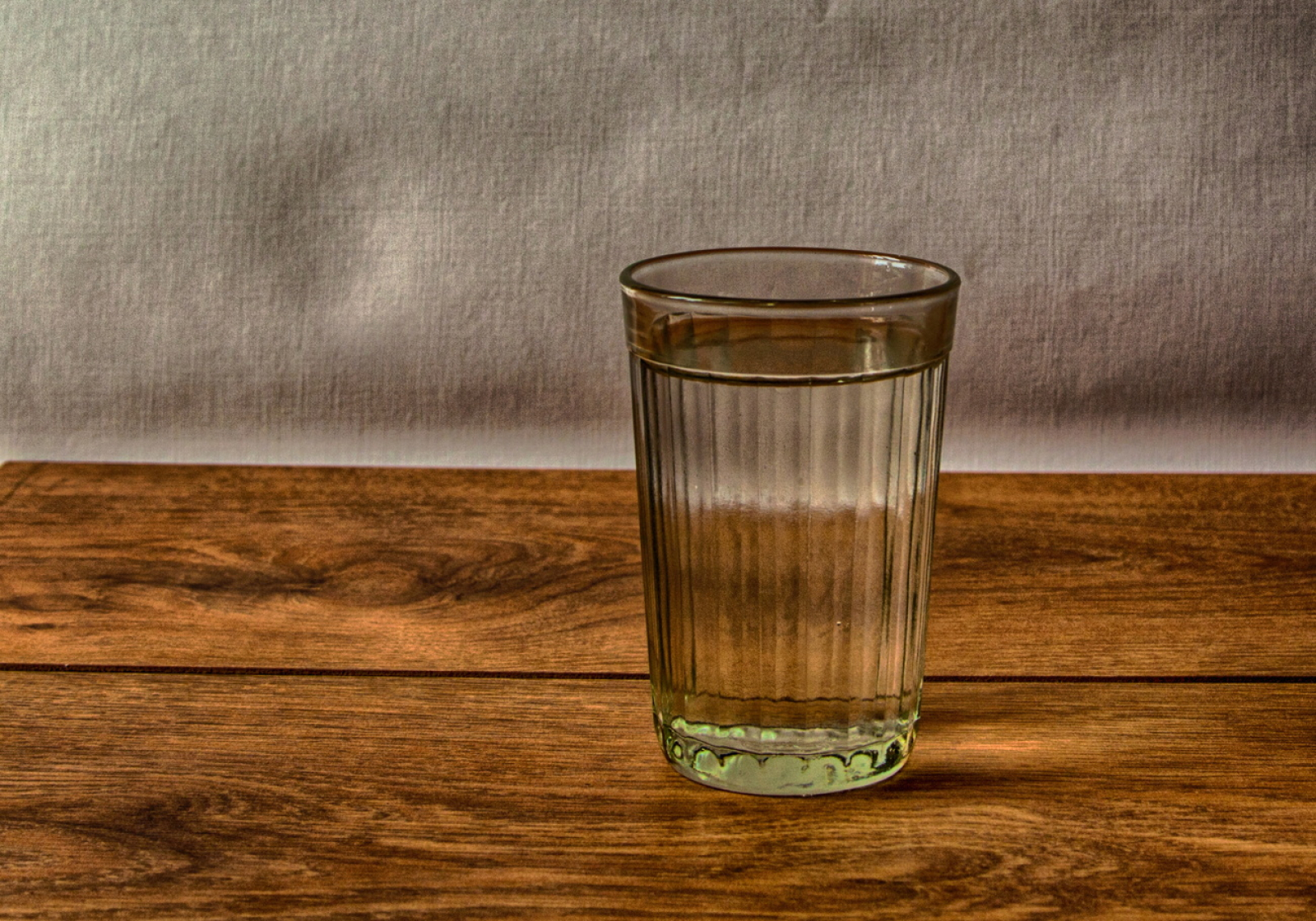 На столе стоят три склянки с водой. Стакан. Граненый стакан. Граненый стакан с водой. Стакан воды на столе.